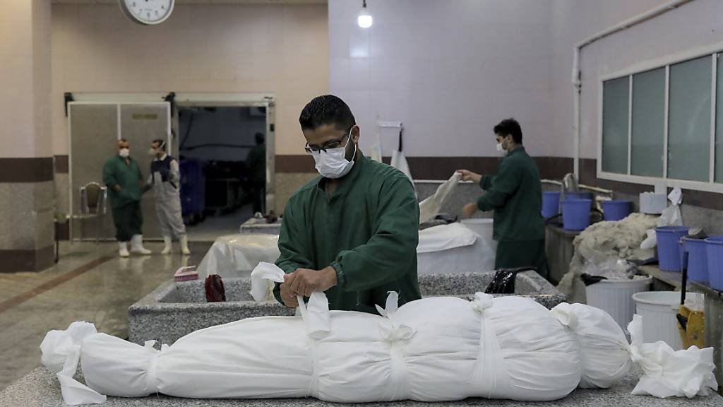 dpatopbilder - Ein Mitarbeiter bereitet in einem Leichenschauhaus in Teheran den Leichnam eines Mannes vor, der an den Folgen einer Corona-Infektion gestorben ist. Foto: Ebrahim Noroozi/AP/dpa