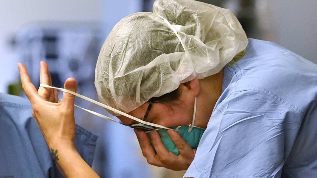 Eine Krankenschwester setzt eine N-95-Maske auf, bevor sie die «rote Zone» betritt. Foto: Elaine Thompson/AP/dpa