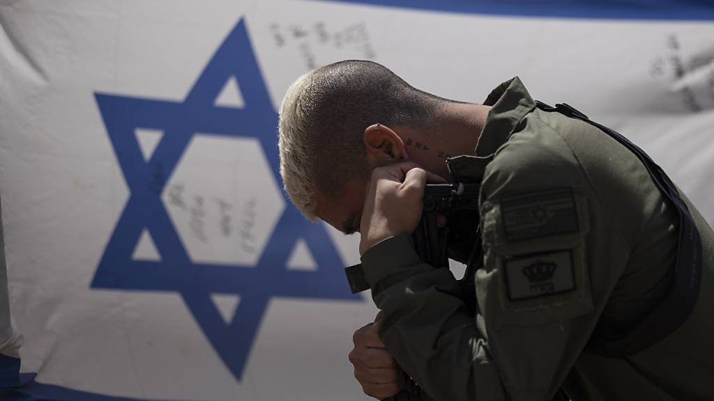 Ein Armeeangehöriger aus Israel kniet vor der Landesflagge zu den Feierlichkeiten zum jährlichen israelischen Gedenktag für die gefallenen Soldaten. (Archivbild)