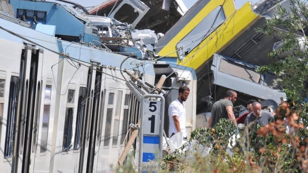 Rettungsteams im Einsatz bei den völlig zerstörten Eisenbahnwaggons in Süditalien - mindestens 20 Menschen starben bei dem Unglück.