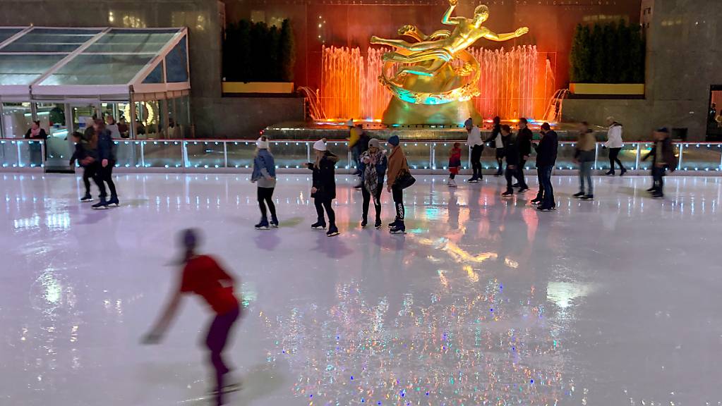 ARCHIV - Auf der Eisfläche der Schlittschuhbahn am Rockefeller Center spiegeln sich die bunten Lichter des wohl berühmtesten Weihnachtsbaums der Welt. Foto: Benno Schwinghammer/dpa