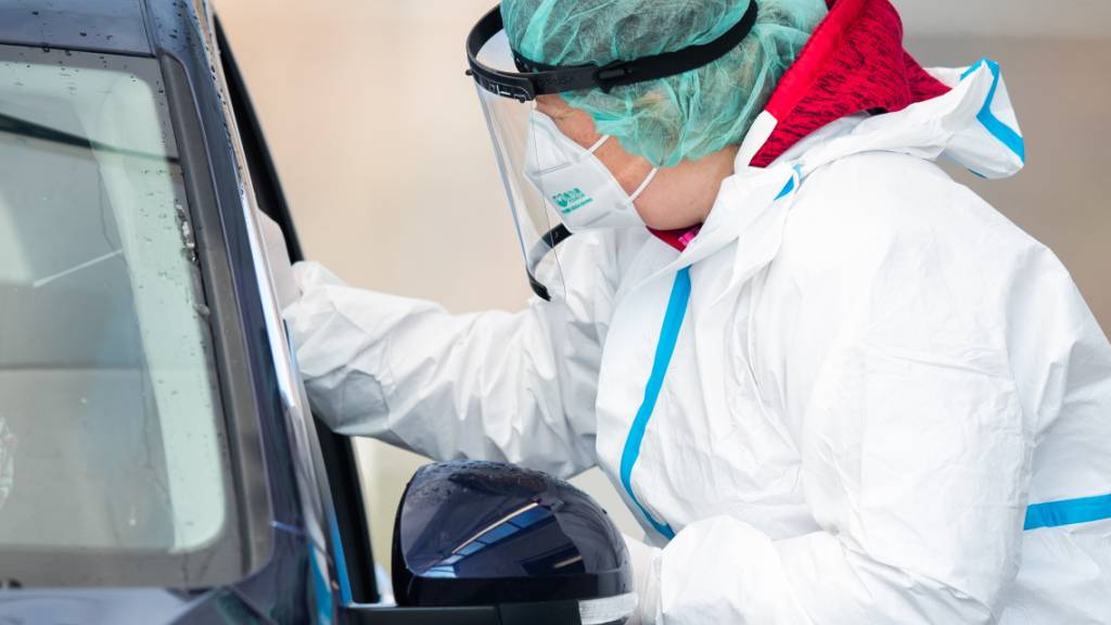 Eine Mitarbeiterin macht in einem Corona-Abstrich-Zentrum bei einem Autofahrer einen Abstrich für einen Corona-Test. Foto: Tom Weller/dpa