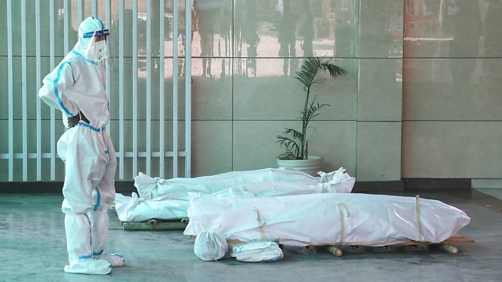 Ein Angehöriger steht in einem indischen Krematorium vor dem Leichnam eines verstorbenen Corona-Patienten.