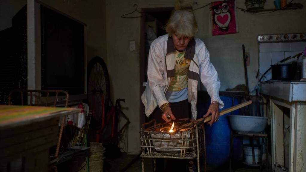 ARCHIV - Minorkys Hoyos Ruiz zündet während eines Stromausfalls Kohlen an, um das Abendessen zu kochen. Foto: Ramon Espinosa/AP/dpa (Archivbild)