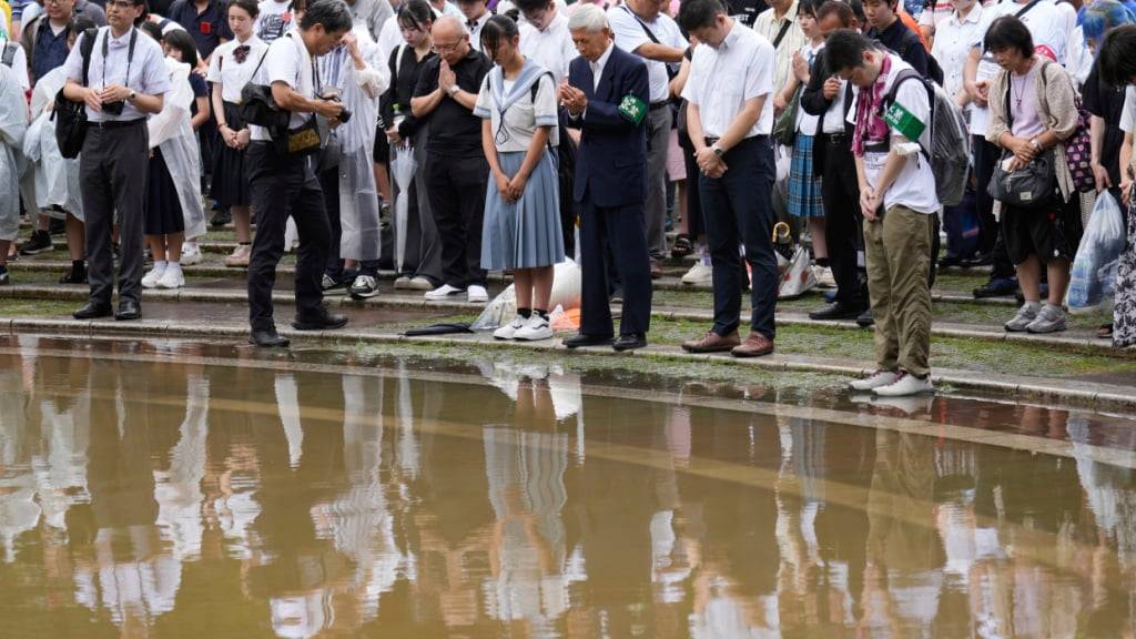 Menschen legen eine Schweigeminute im Atomic Bomb Hypocenter Park ein. Foto: Eugene Hoshiko/AP/dpa