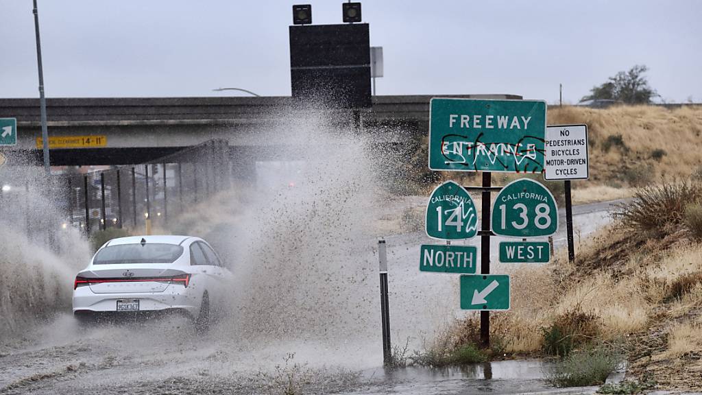 Ein Auto fährt durch eine überflutete Autobahnauffahrt in der Nähe von Palmdale, als Tropensturm «Hilary» auf das Gebiet zusteuert. Foto: Richard Vogel/AP
