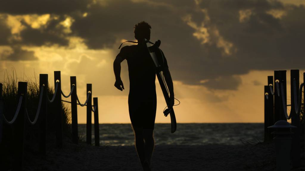 Ein Surfer geht zum Strand in Surfside im US-Bundesstaat Florida am Atlantik. (Archivbild)