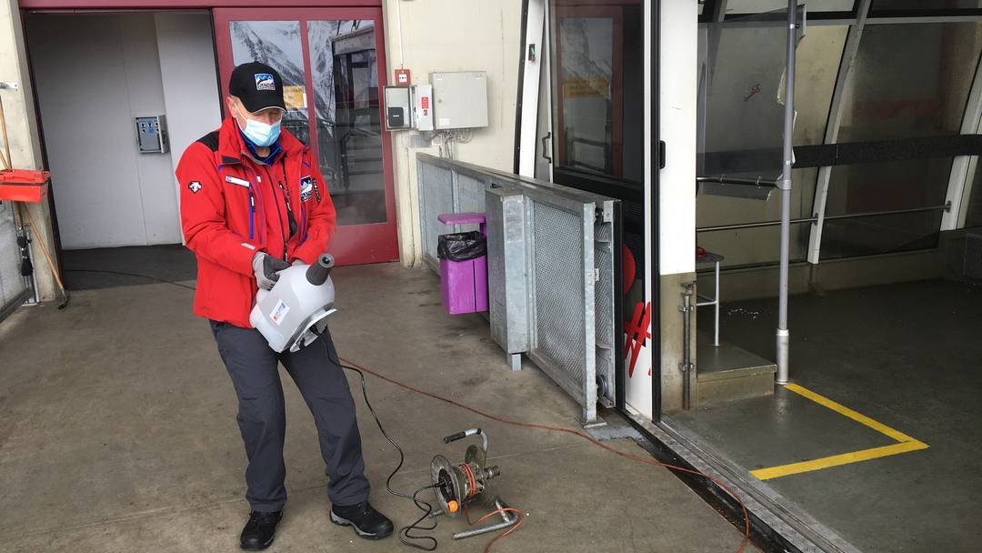 A cable car employee in Valais is using a cold fogger that sprays disinfectant vapor.