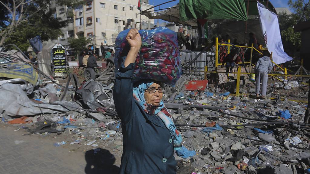 Eine Palästinenserin geht während einer vorübergehenden Waffenruhe zwischen Israel und der palästinensischen Terrororganisation Hamas an zerstörten Gebäuden vorbei. Foto: Hatem Ali/AP/dpa