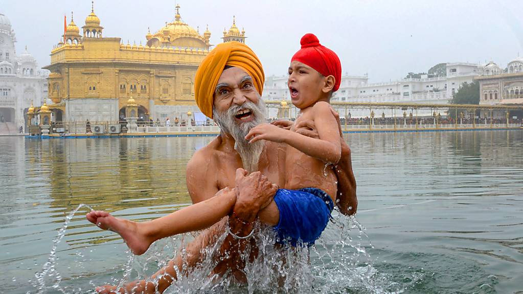 dpatopbilder - Ein Sikh-Gläubiger nimmt mit einem Familienmitglied ein heiliges Bad im «Sarovar» während des Makar-Sankranti-Festes. Foto: Shiva Sharma/PTI/dpa