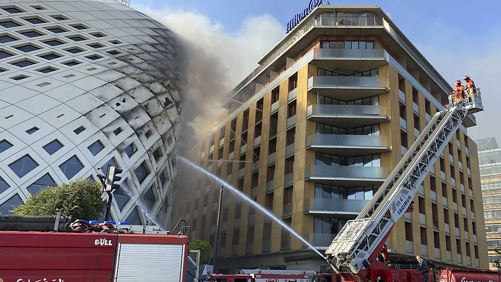 Feuerwehrleute löschen einen Brand im Geschäftsviertel der libanesischen Hauptstadt. Betroffen ist das sich noch im Bau befindlichen Gebäude (l), das von der Architektin Zaha Hadid entworfen wurde. Foto: Fadi Tawil/AP/dpa