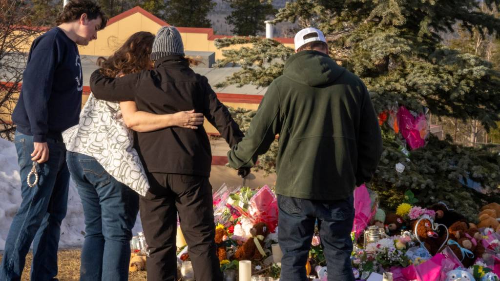 ARCHIV - Anwohner umarmen sich, während sie Blumen an einer Gedenkstätte für die Opfer der Massenschießerei in Tumbler Ridge niederlegen. Foto: Christinne Muschi/The Canadian Press/AP/dpa