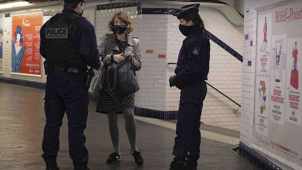 In einer U-Bahn-Station in Paris kontrollieren zwei Polizisten eine Pendlerin. Im Kampf gegen die Corona-Pandemie gelten in Frankreich weitreichende Ausgangsbeschränkungen. Foto: Thibault Camus/AP/dpa