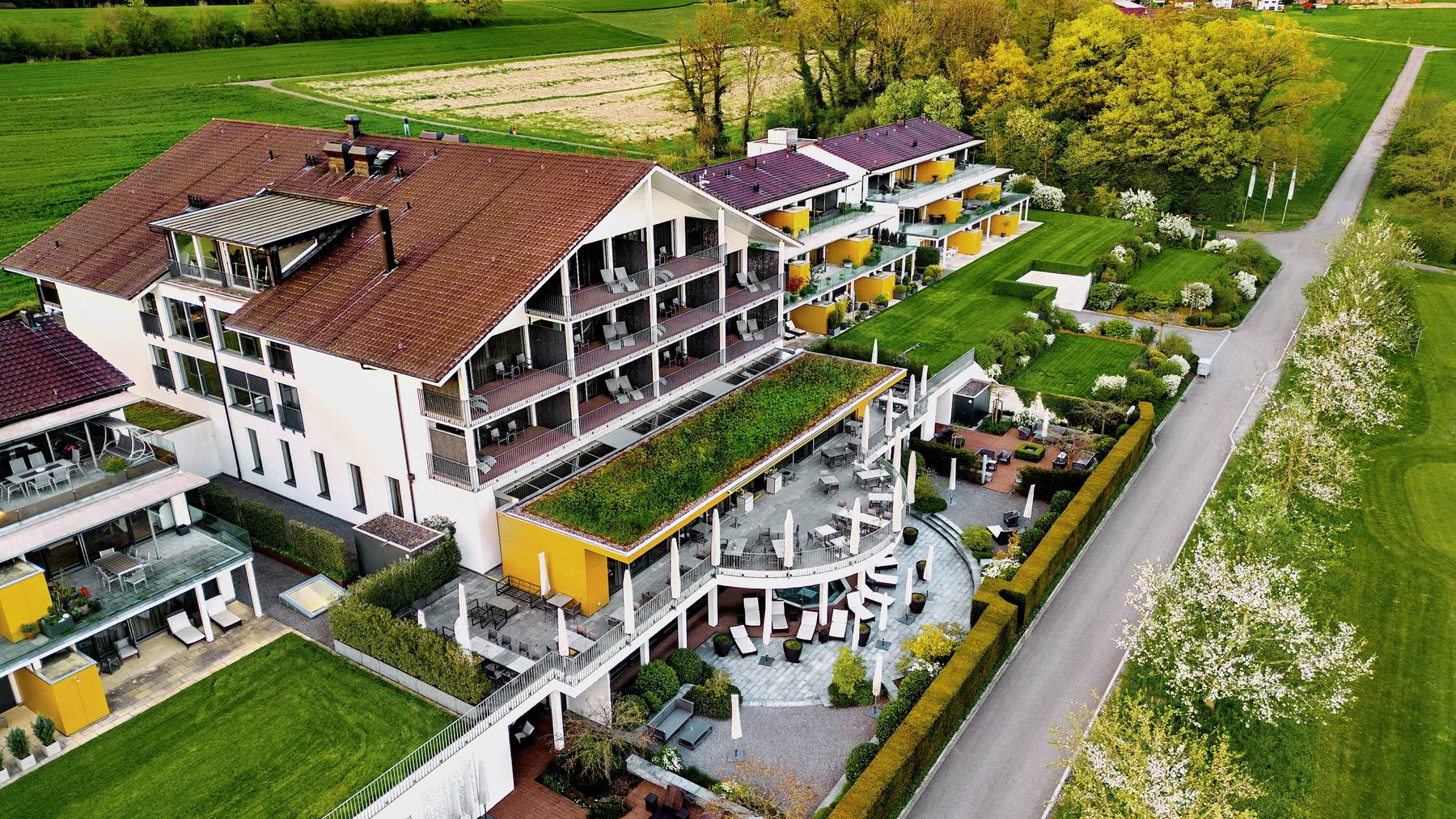 Golfpanorama_Hotel_Golf_Aussenfassade_Apfelbäume_Mai_Ansicht von oben_Gebäude