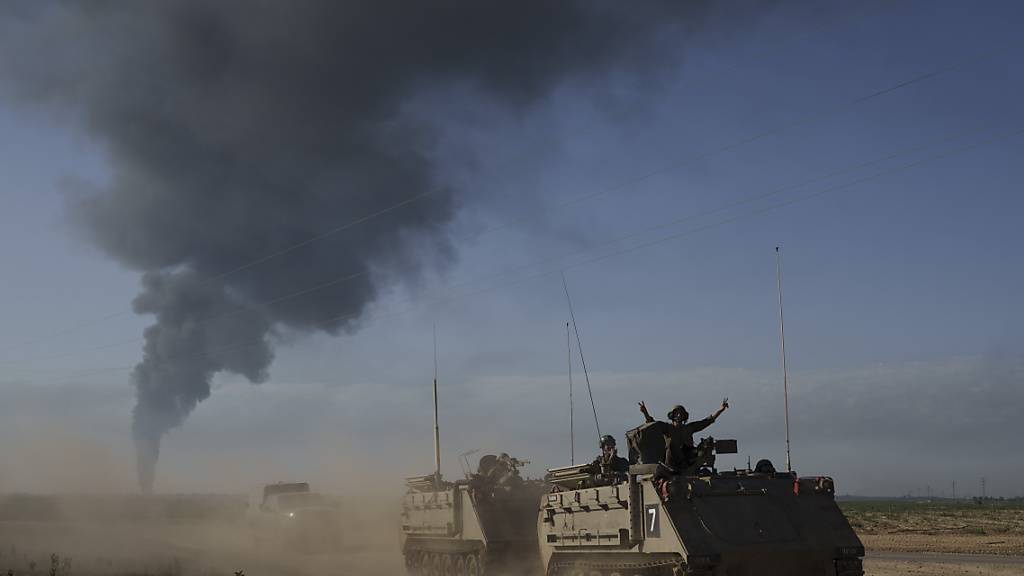 Israelische Soldaten auf gepanzerten Mannschaftstransportern (APC) der Armee nahe der Grenze zwischen Israel und Gaza, während im Gazastreifen Rauch in den Himmel steigt, vom Süden Israels aus gesehen. Foto: Leo Correa/AP/dpa