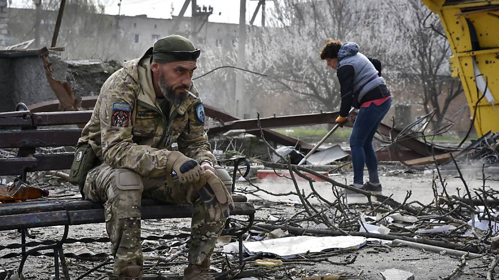 Ein ukrainischer Soldat raucht, während ein Anwohner Trümmer in der Region Saporischschja aufräumt. Durch russische Raketentreffer wurden hier kürzlich mindestens vier Menschen getötet. Foto: Andriy Andriyenko/AP/dpa