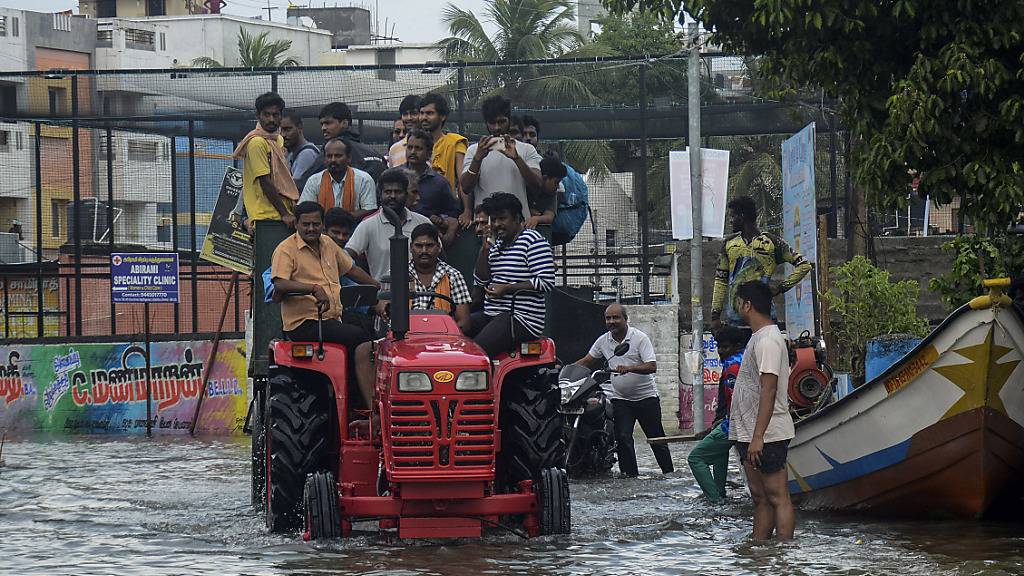 Nach schweren Regenfällen an der Küste Südindiens werden Bewohner auf einem Traktor aus überfluteten Gebieten evakuiert. Der Tropensturm Michaung brachte sintflutartige Regenfälle und starke Winde mit sich. Foto: Uncredited/AP/dpa