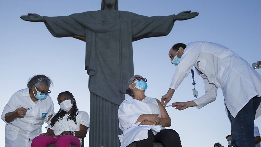 dpatopbilder - Zwei Frauen erhalten bei einm Impftermin vor der Christus-Statue eine Covid-19-Impfung. Foto: Fernando Souza/dpa