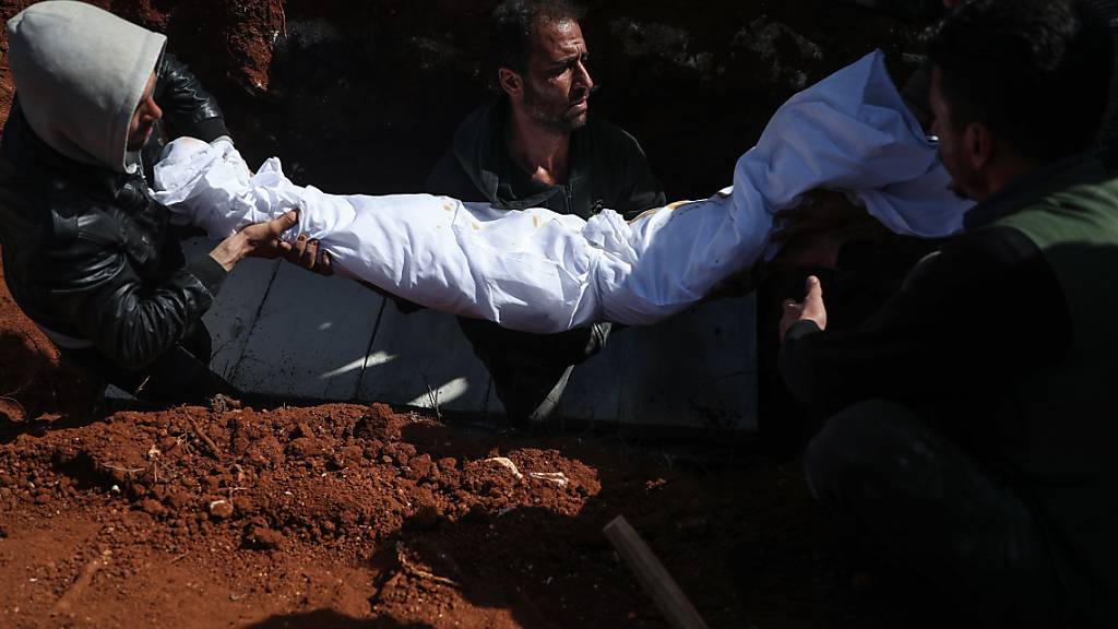 Syrische Männer tragen während einer Beerdigung auf einem Friedhof den Leichnam einer Person, die bei einem Raketenangriff auf ein Krankenhaus getötet wurden. In Syrien sind bei einem Angriff von Regierungstruppen auf ein Krankenhaus nach Angaben von Menschenrechtlern mindestens fünf Menschen getötet worden. Foto: Anas Alkharboutli/dpa