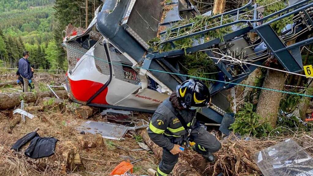Rettungskräfte arbeiten am Wrack einer abgestürzten Gondel, die in einem Waldstück liegt. Nach dem Seilbahnunglück in Italien soll die Unglücksgondel mit einem Hubschrauber abtransportiert werden.