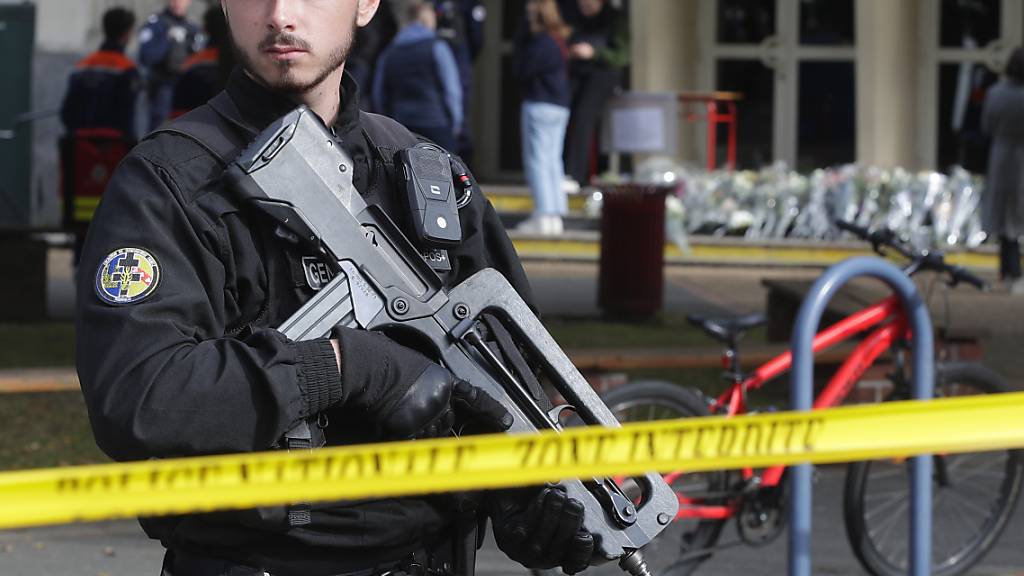 ARCHIV - Ein Polizist bewacht den Eingang eines Gymnasiums. Die französischen Behörden teilen mit, dass das Gymnasium, in dem letzte Woche ein Lehrer mit einem Messer getötet wurde, wegen eines Bombenalarms evakuiert wurde. Foto: Michel Spingler/AP/dpa