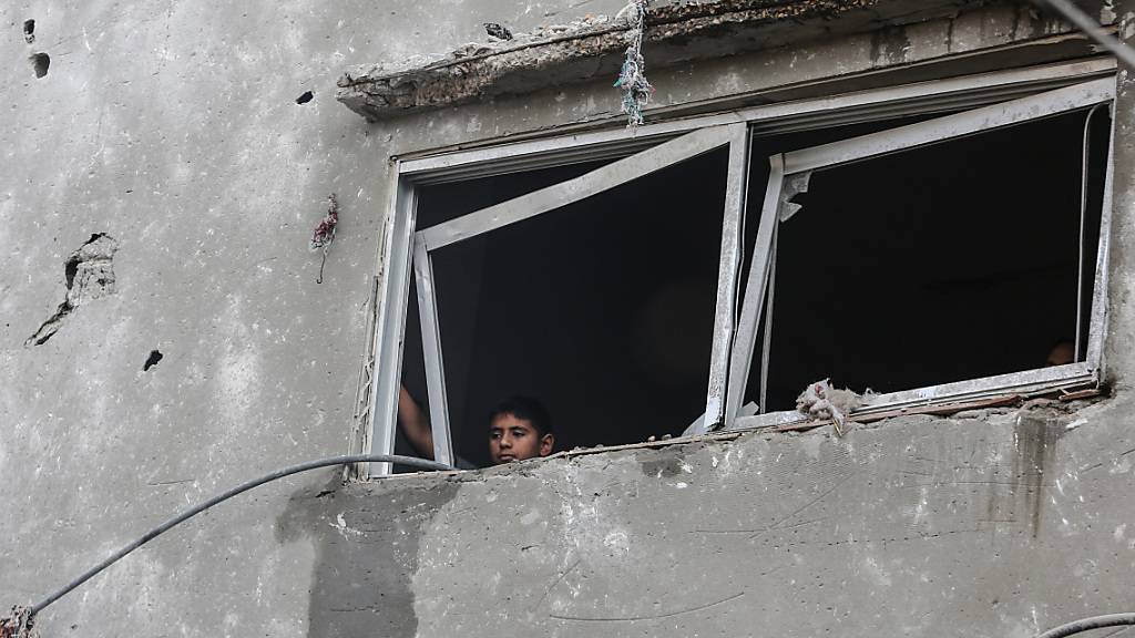 Ein kleiner palästinensischer Junge blickt aus dem Fenster eines zerstörten Gebäudes. Foto: Mohammed Talatene/dpa