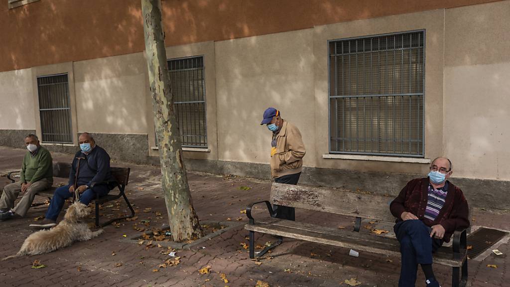 Ältere Menschen sitzen in einem Park in Vallecas, einem ärmeren Madrider Viertel, das teilweise abgeriegelt ist. Foto: Bernat Armangue/AP/dpa
