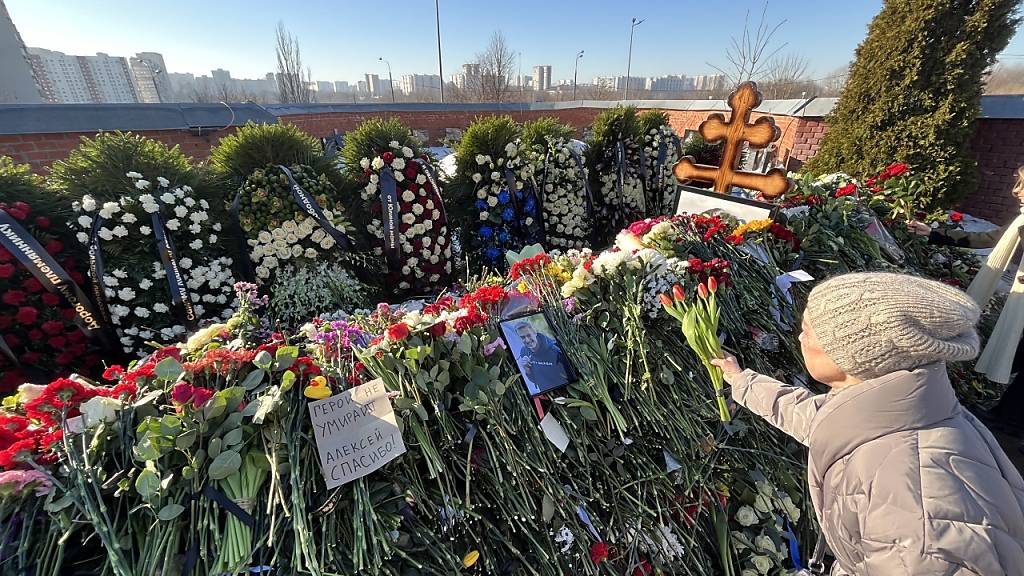 Ein Frau legt nach der Beerdigung von Alexej Nawalny auf dem Borisowskoje-Friedhof Blumen am Grab ab. Foto: Ulf Mauder/dpa