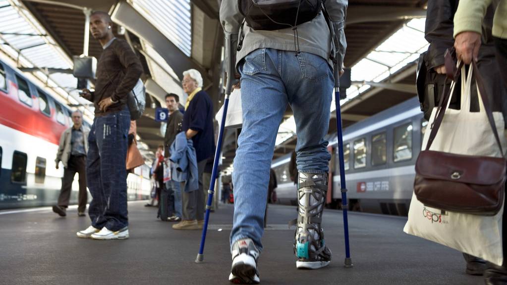 Mann an Krücken an einem Schweizer Bahnhof