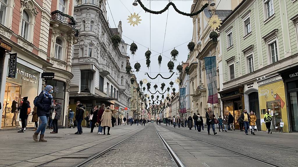 ARCHIV - Menschen mit Mund-Nasen-Schutz gehen in der Innenstadt von Graz an Geschäften vorbei. (Archivbild) Foto: Ingrid Kornberger/APA/dpa