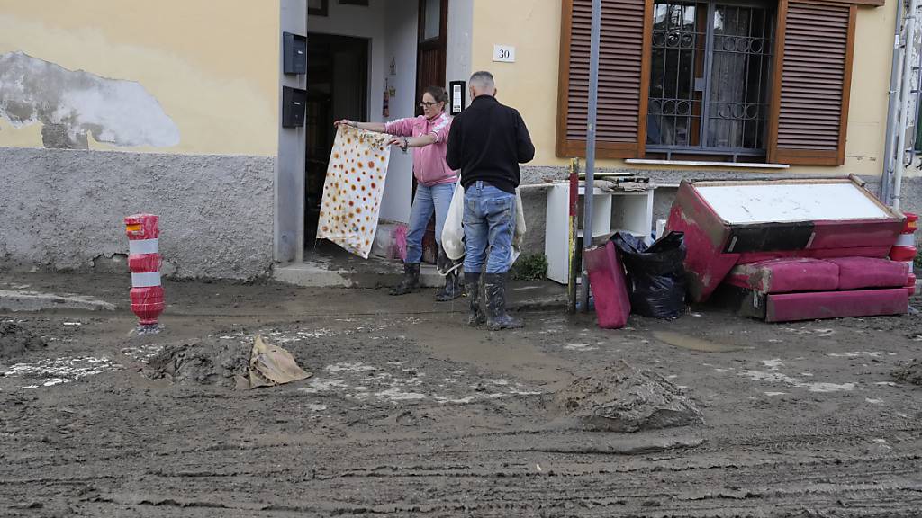 Menschen retten ihre Habseligkeiten aus ihren von Schlamm überfluteten Häuser. Schwere Unwetter mit heftigen Regenfällen haben die mittelitalienische Region Toskana in der Nacht zum Freitag heimgesucht. Foto: Gregorio Borgia/AP/dpa