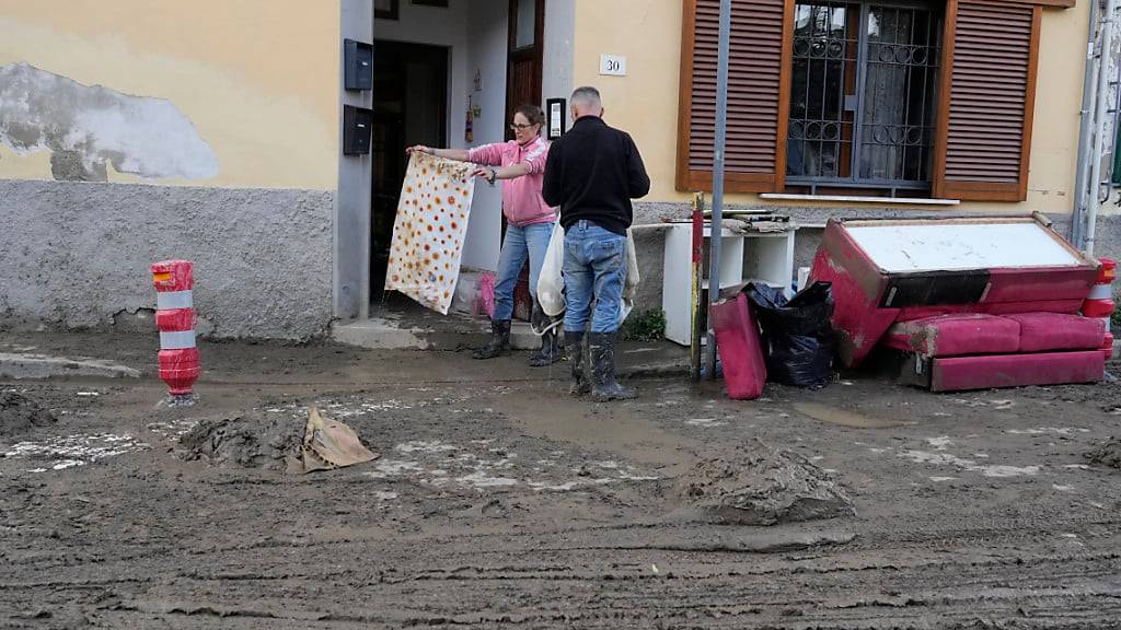 Menschen retten ihre Habseligkeiten aus ihren von Schlamm überfluteten Häuser. Schwere Unwetter mit heftigen Regenfällen haben die mittelitalienische Region Toskana in der Nacht zum Freitag heimgesucht. Foto: Gregorio Borgia/AP/dpa