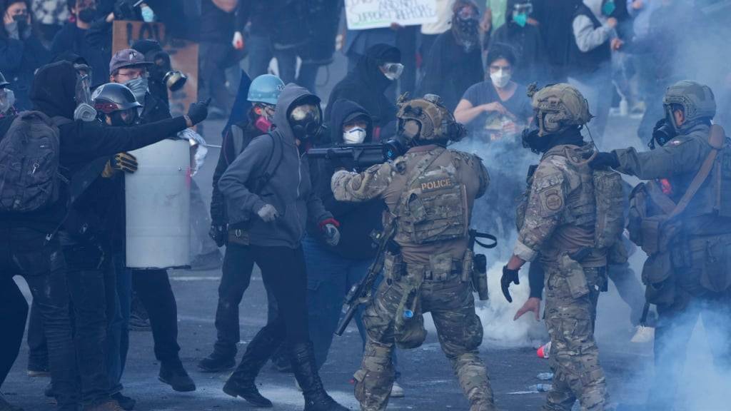 ARCHIV - Beamte der US-Zollbehörde setzen Tränengas gegen Demonstranten ein, während einer Demonstration vor dem Gebäude der US-Zoll- und Einwanderungsbehörde (ICE). Foto: Jenny Kane/AP/dpa
