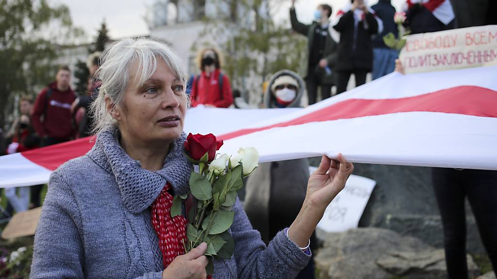 dpatopbilder - Eine Frau hält bei einer Demonstration Rosen und die historische weiß-rot-weiße Fahne in der Hand. Tausende Menschen, darunter vor allem Senioren und Studenten, marschierten am Montag durch die Hauptstadt. Foto: -/AP/dpa