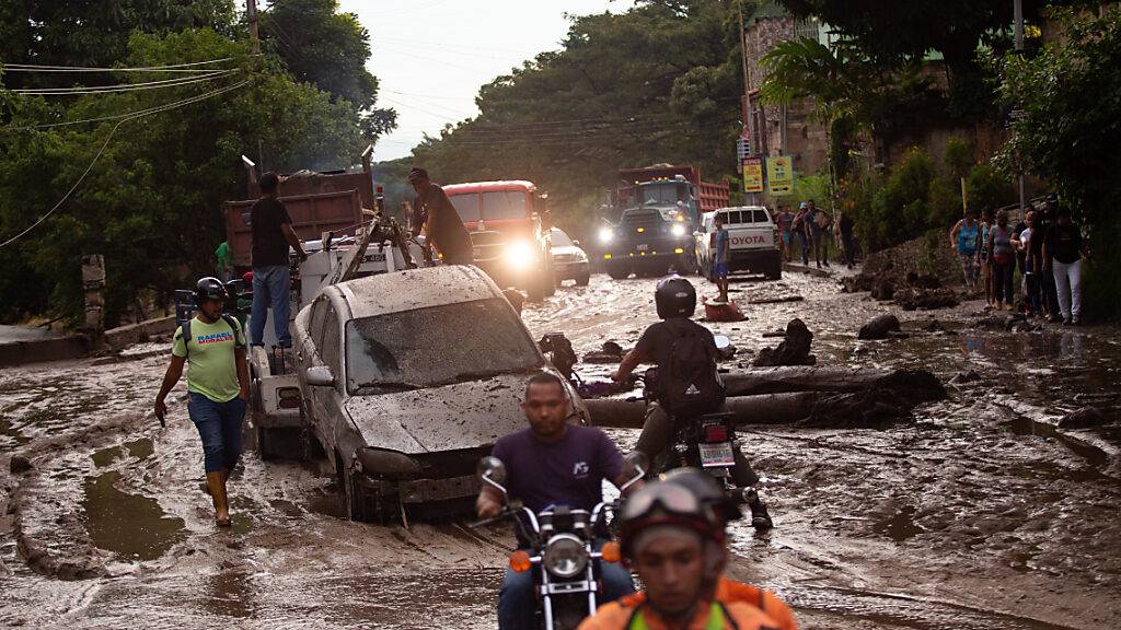 dpatopbilder - Menschen und Fahrzeuge stecken im Schlamm der durch Überschwemmungen und Erdrutsche auf die Straßen kam. Foto: Juan Carlos Hernandez/ZUMA Press Wire/dpa