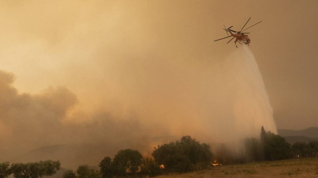 Ein Hubschrauber wirft Wasser über einem Waldbrand im Dorf Dikela in der Nähe der Stadt Alexandroupolis ab. Foto: Achilleas Chiras/AP