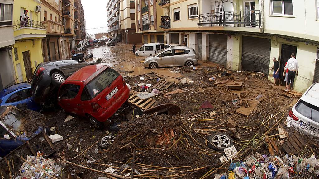 Von den Wassermassen der Überschwemmungen übereinander geschobene Autos liegen in einer überfluteten Straßen. Foto: Alberto Saiz/AP