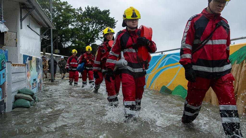 Feuerwehrleute gehen durch das Hochwasser im Gebiet Lei Yue Mun, während sich der Supertaifun «Ragasa» nähert. Foto: Chan Long Hei/AP/dpa