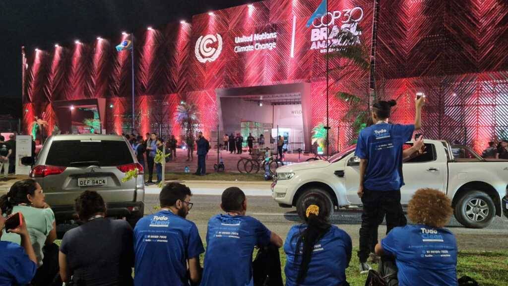 Reinigungskräfte sitzen vor dem Veranstaltungsort des UN-Klimagipfels COP30, nachdem Aktivisten dort eingedrungen waren und sie das Gelände verlassen mussten. Foto: Larissa Schwedes/dpa