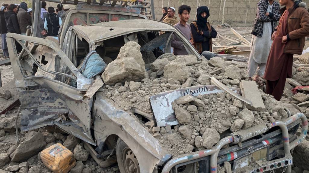 ARCHIV - Anwohner stehen neben einem beschädigten Auto am Ort eines grenzüberschreitenden Angriffs der pakistanischen Armee in der Provinz Nangarhar. Foto: Hedayat Shah/AP/dpa