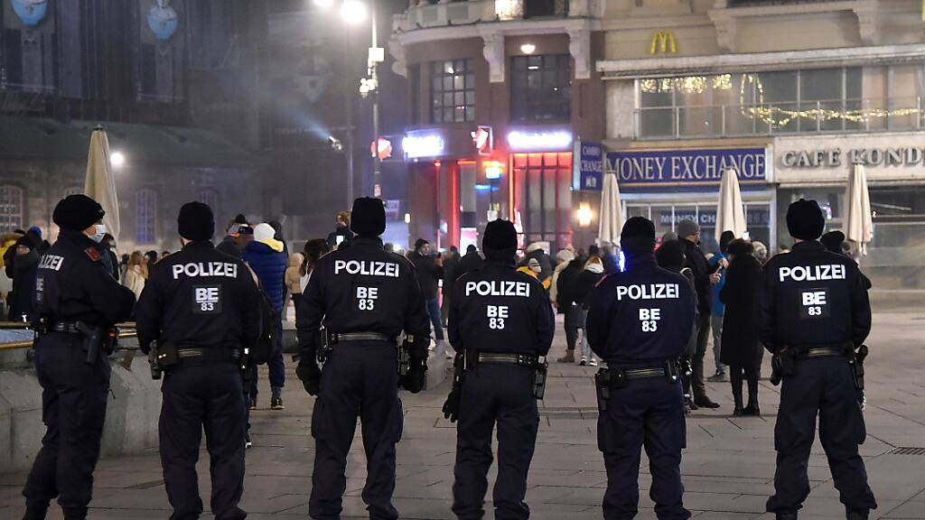 Polizeibeamte beobachten in der Innenstadt das Geschehen in der Silvesternacht. In Österreich galten verschärfte Ausgangsbeschränkungen. Foto: Hans Punz/APA/dpa