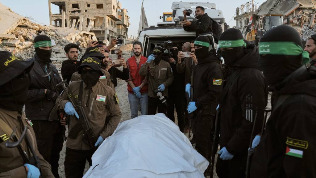 Maskierte Kämpfer des Islamischen Dschihad und der Hamas übergeben im nördlichen Gazastreifen einen Leichensack, der vermutlich die Überreste einer verstorbenen Geisel enthält, an das Rote Kreuz zur Übergabe an israelische Behörden. Foto: Jehad Alshrafi/AP/dpa