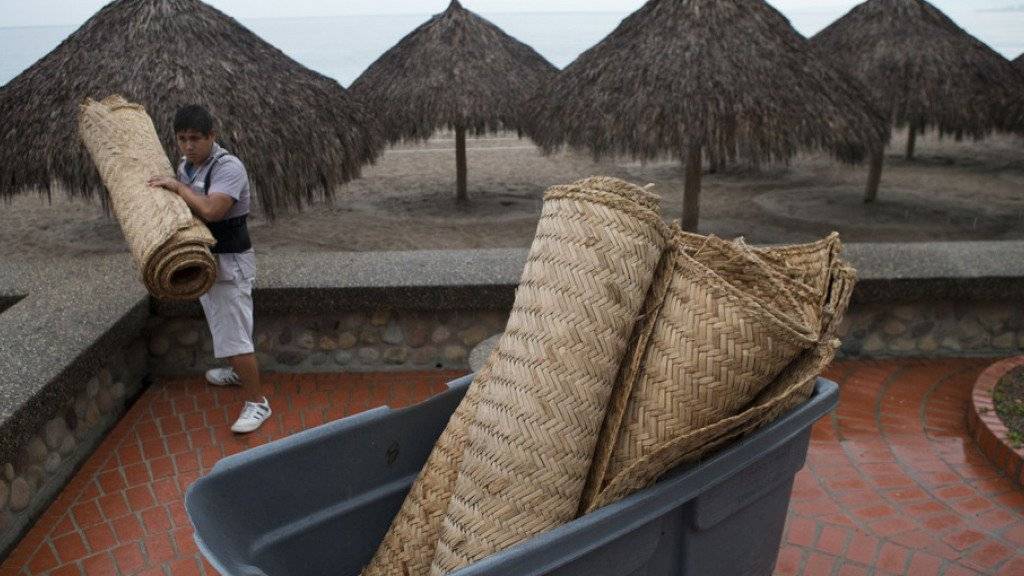 Ein Hotelangestellter in Puerto Vallarta rollt am Strand Matten zusammen. Der beliebte Ferienort an der mexikanischen Küste könnte nach Behördenangaben direkt vom Hurrikan «Patricia» getroffen werden
