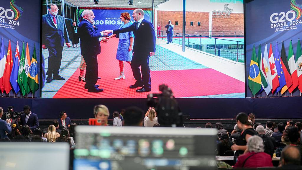 Auf einer riesigen Monitorwand im Pressezentrum ist die Begrüßung von Bundeskanzler Olaf Scholz (SPD, r) und seiner Ehefrau Britta Ernst durch Lula da Silva, Präsident der Republik Brasilien, beim G20-Gipfel zu sehen. Foto: Kay Nietfeld/dpa