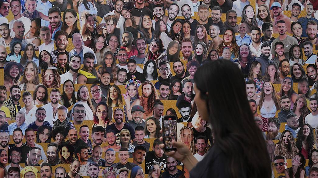 ARCHIV - Eine Frau fotografiert eine Wand mit Porträts der Opfer am Ort des Nova-Musikfestivals, bei dem Hunderte von Feiernden getötet und von der islamistischen Hamas entführt und in den Gazastreifen verschleppt wurden. Der Angriff der islamistischen Hamas jährt sich zum ersten Mal. Foto: Ariel Schalit/AP/dpa