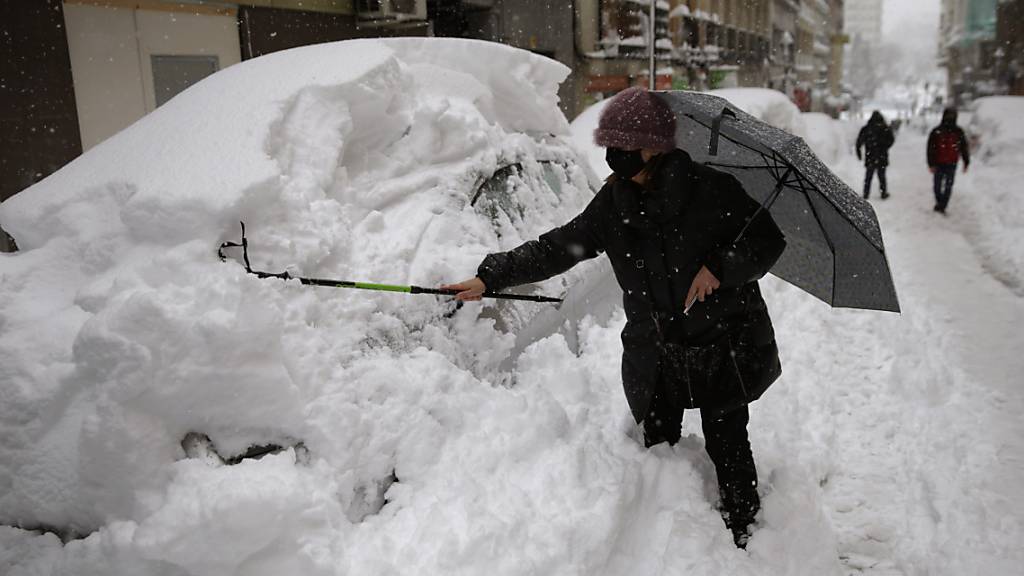 Eine Frau in Madrid befreit ihr Auto von einer hohen Schneeschicht. Foto: Andrea Comas/AP/dpa