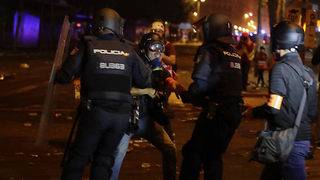 Polizisten nehmen bei den Protesten in Barcelona am Abend einen Fotografen der Zeitung «El Pais» fest.