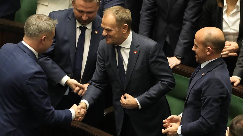 Der neu gewählte polnische Ministerpräsident Donald Tusk (M) wird von Abgeordneten beglückwünscht, nachdem seine Regierung die Vertrauensabstimmung im Parlament bestanden hat. Foto: Czarek Sokolowski/AP