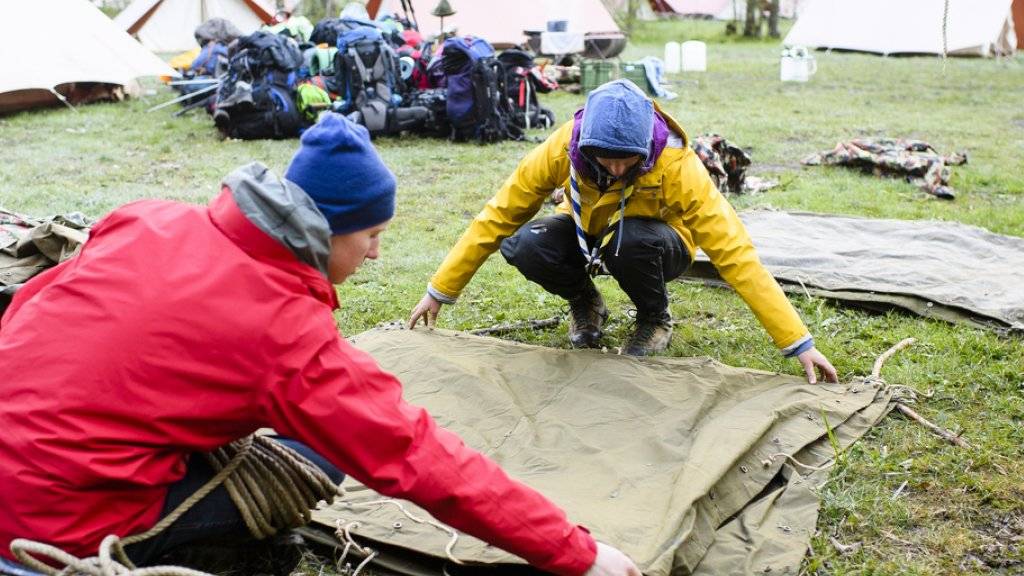 Zelt aufbauen, Zelt abbauen, und dazwischen viel erleben: Zwei Pfadfinder legen während eines Pfingstlagers in Kandersteg BE Zeltblachen übereinander. (Archiv)