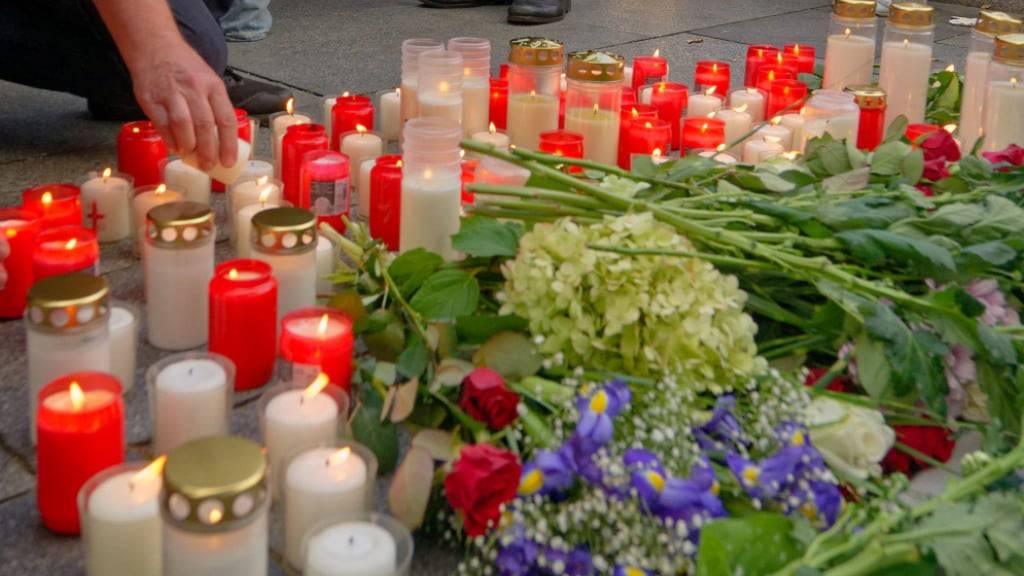 Menschen legen in Gedenken an die Opfer der Messerattacke auf dem Solinger Stadtfest Blumen ab und zünden Kerzen an. Foto: Henning Kaiser/dpa